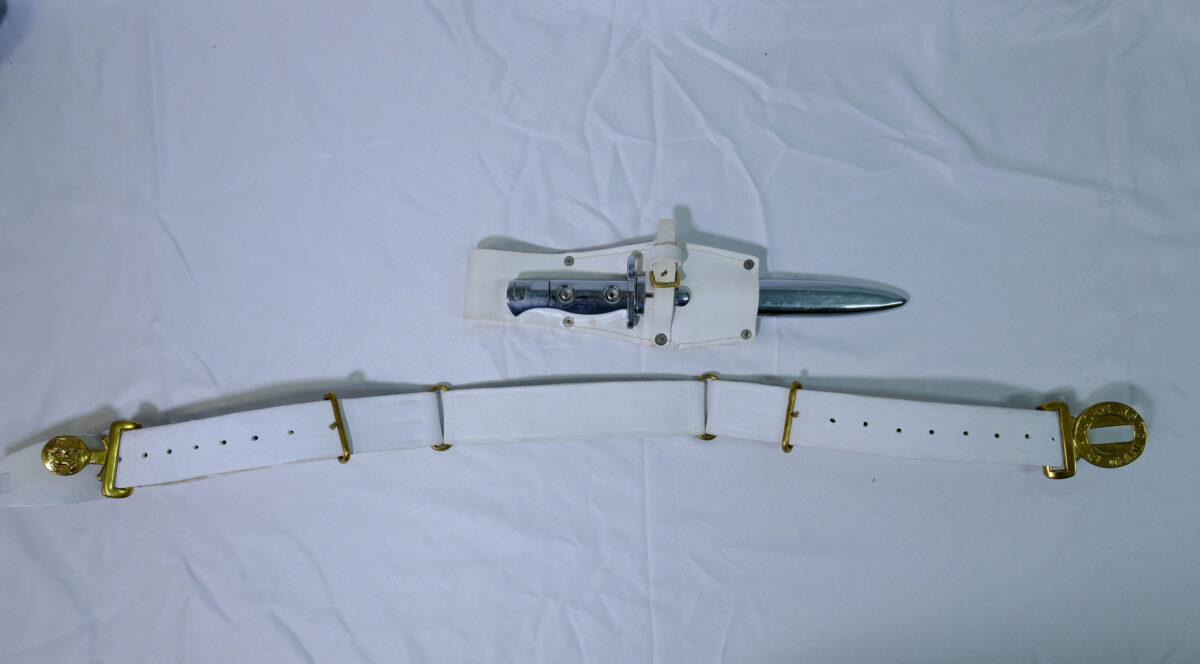White ceremonial parade belt and bayonet frog featuring polished brass fittings and an accompanying bayonet/scabbard White ceremonial parade belt and bayonet frog featuring polished brass fittings and an accompanying bayonet/scabbard