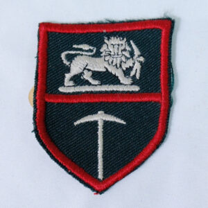 This is an original Rhodesian Army general service cloth shoulder patch (formation sign), featuring an embroidered silver lion holding a tusk above a mining pick on a dark field with a red border. This is an original Rhodesian Army general service cloth shoulder patch (formation sign), featuring an embroidered silver lion holding a tusk above a mining pick on a dark field with a red border.